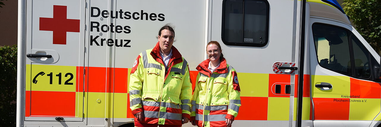 Zwei Rettungsdienstmitarbeiter stehen vor einem Rettungswagen.